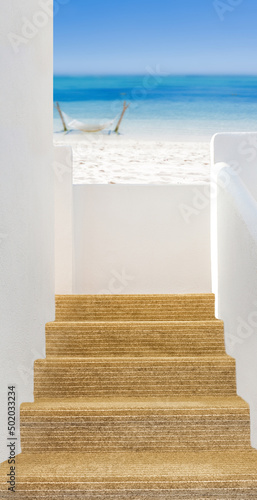 Escalier menant à une terrasse avec vue sur plage paradisiaque de sable blanc © Unclesam