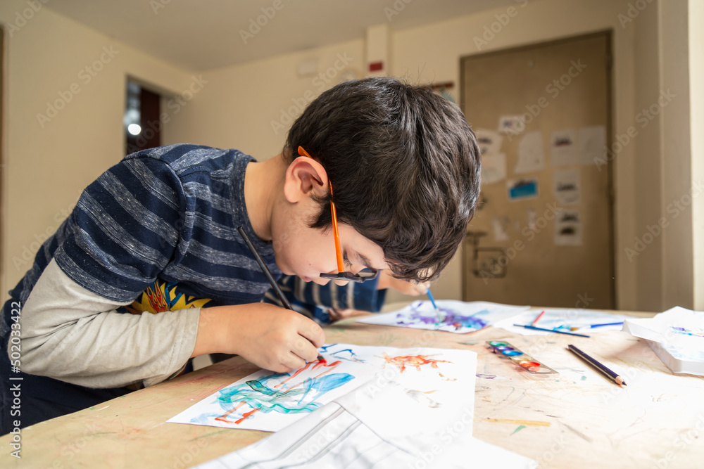 child painting with paints and colored pencil laughing making a drawing child painting with paints and colored pencil laughing making a drawing