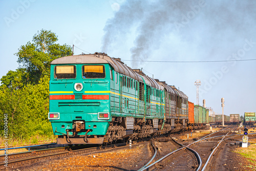 Four powerful locomotives with a long freight train depart from the sorting station. Freight railway transportation of metal products. Sunset lighting. photo