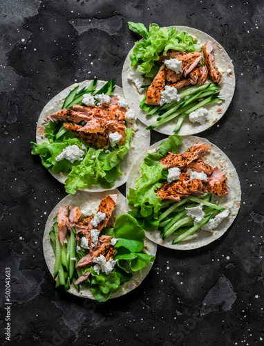 Grilled salmon, iceberg lettuce, cucumber and homemade mayonnaise tortilla sauce on a dark background. Delicious appetizer, tapas