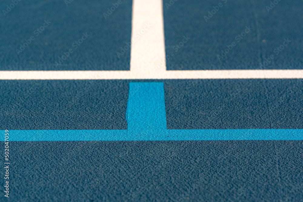 Blue tennis court with white lines and light blue pickleball lines