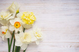 Daffodil flowers on a wooden light background, place for text. Top view.