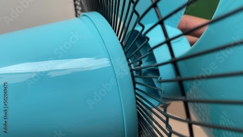 Tighten black plastic nut at blue blade electric fan. Hand fasten bolt rotate counterclockwise installing to lock fan blade daytime. - DIY household self assembly concept photo