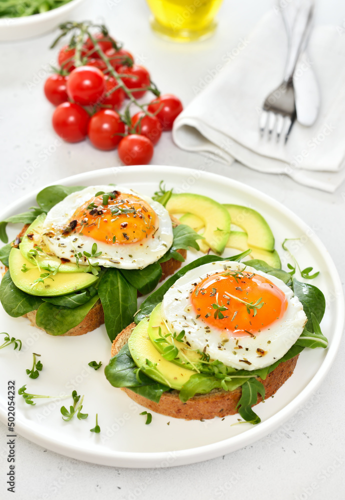 Bread with fried eggs, avocado and greens