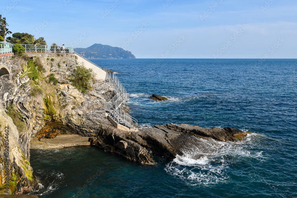 View of the Paradise Gulf from the Anita Garibaldi Promenade with ladders on the cliff and the promontory of Portofino on the sea horizon, Nervi, Genoa, Liguria, Italy