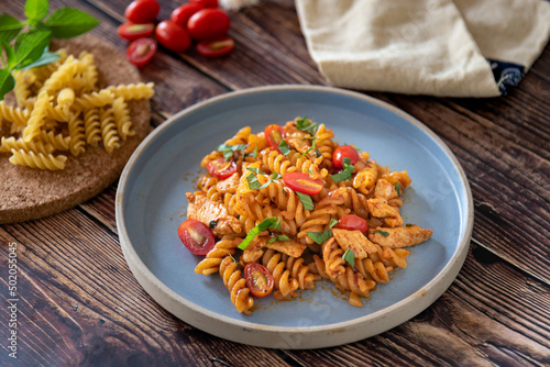 Fusilli pasta stir fired with tomato sauce and chicken, homemade Italian food photo