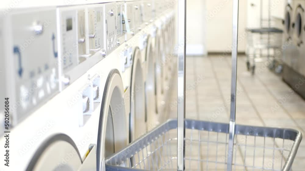 Row of washing and drying machines, public coin laundry in California, USA. Drums of washers and dryers in self-service laundromat or commercial laundrette. Automatic launderette in United States. Row of washing and drying machines, public coin laundry in California, USA. Drums of washers and dryers in self-service laundromat or commercial laundrette. Automatic launderette in United States.