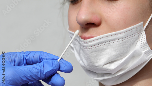 nose of the young girl while a nasal swab test is performed for the search of the coronavirus virus with mask