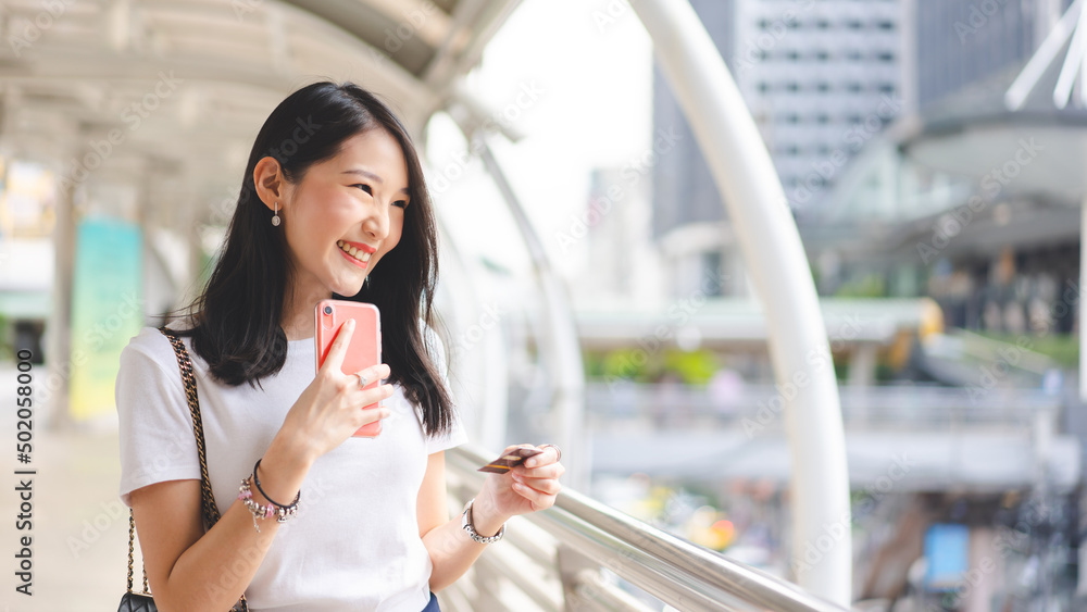 Young adult asian woman using creadit card and smartphone for online shopping and digital wallet