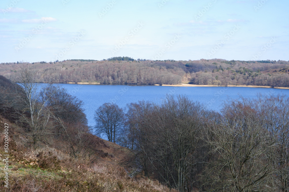 Landscape in early spring. A beautiful lake surrounded by hills with trees without leaves. Early spring. Spring landscape with trees by the river Landscape in early spring. A beautiful lake surrounded by hills with trees without leaves. Early spring. Spring landscape with trees by the river