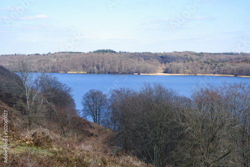 Fototapeta Naklejka Na Ścianę i Meble -  Landscape in early spring. A beautiful lake surrounded by hills with trees without leaves. Early spring. Spring landscape with trees by the river