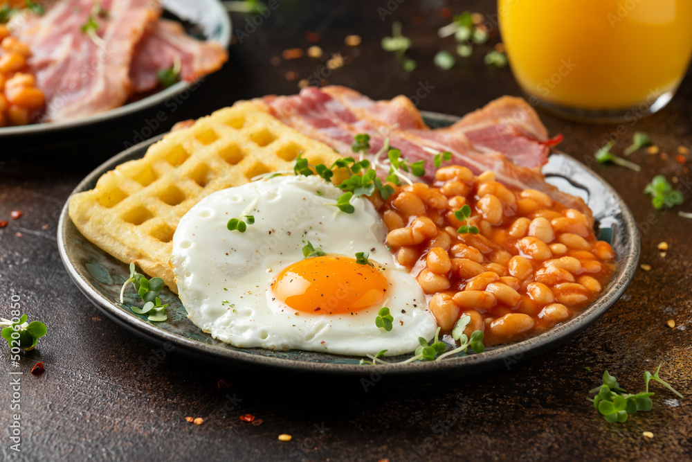 Potato waffles with fried egg, bacon and baked beans. Morning breakfast Potato waffles with fried egg, bacon and baked beans. Morning breakfast