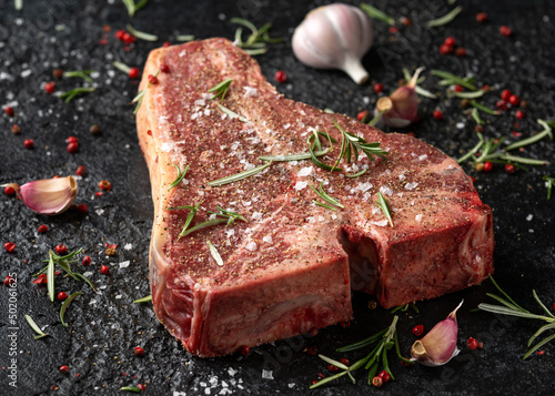 Fototapet Raw T Bone beef steak with herb and seasoning on rustic background