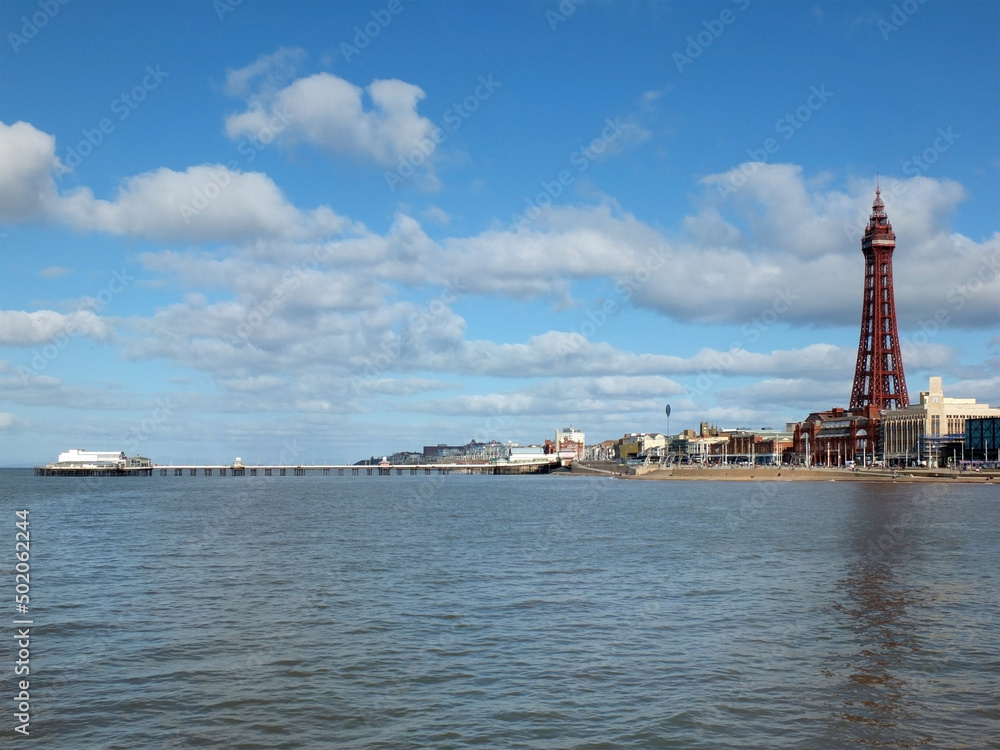 view of of blackpool with the north pier buildings and tower reflected in the sea with a blue cloudy sky