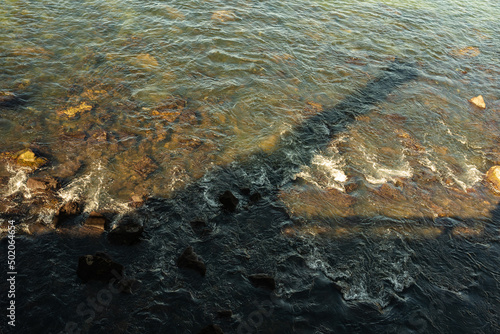 silhouette of the shadow of a cannon reflected in the water and rocks of the sea