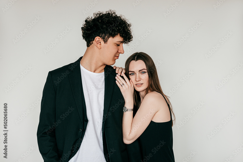 Beautiful couple embracing posing and wearing elegant black outfits and accessories for men and women, white background. Fashion style catalog of clothes for business people, trends of formal wear Beautiful couple embracing posing and wearing elegant black outfits and accessories for men and women, white background. Fashion style catalog of clothes for business people, trends of formal wear