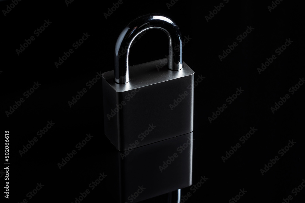 Steel padlock on the black textured background Steel padlock on the black textured background
