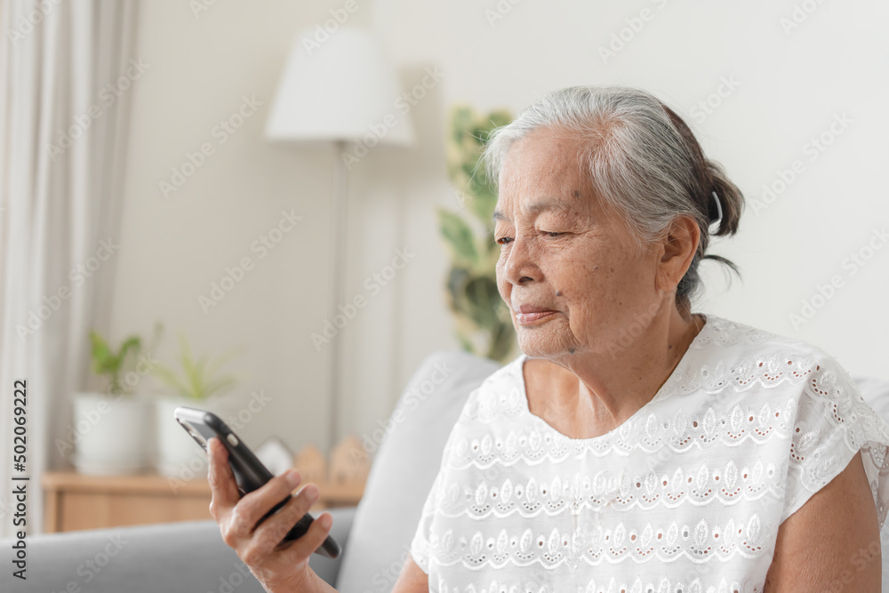 Happy Asian senior woman using smartphone at home. Grandparent call to family member using mobile phone application. Happy Asian senior woman using smartphone at home. Grandparent call to family member using mobile phone application.