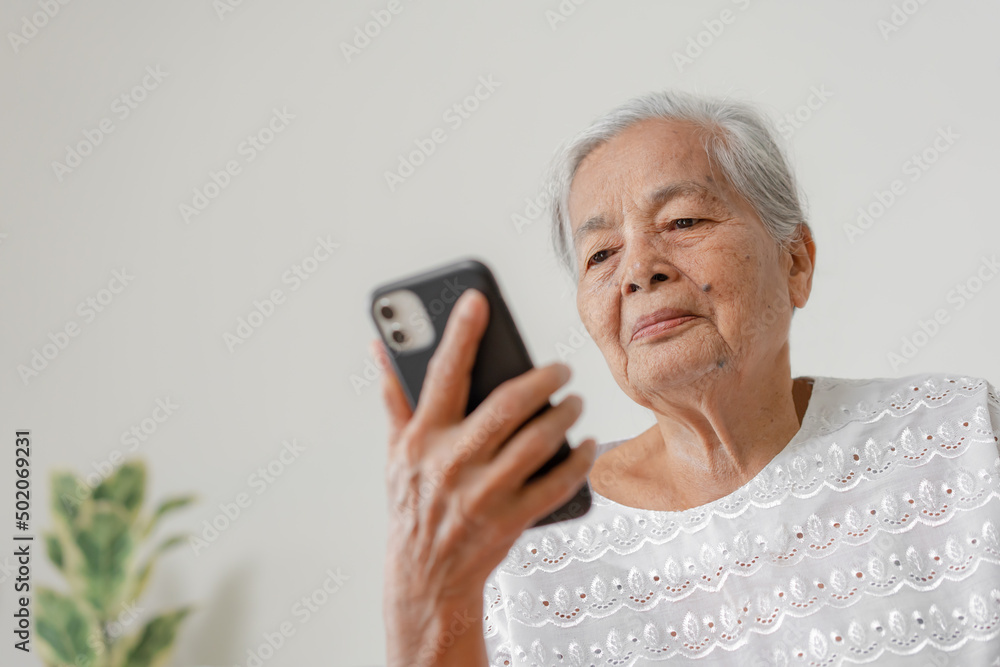 Happy Asian senior woman using smartphone at home. Grandparent call to family member using mobile phone application. Happy Asian senior woman using smartphone at home. Grandparent call to family member using mobile phone application.