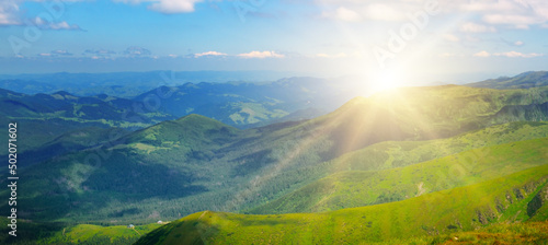 Picturesque mountain slopes, Forests, vast meadows and sun on cloudy skies. Wide photo.