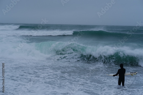 A surfer going into the sea in winter.