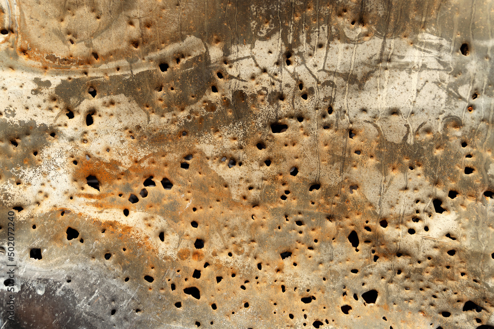 holey rusty metal background. holes from bomb fragments on metal. iron rusty background. bullet holes in a metal plate holey rusty metal background. holes from bomb fragments on metal. iron rusty background. bullet holes in a metal plate