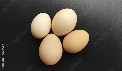 Group of several farm fresh organic brown and white uncooked raw chicken, hen, bird or duck eggs isolated on a black shiny background with copy space. Beautiful horizontal closeup macro top view.