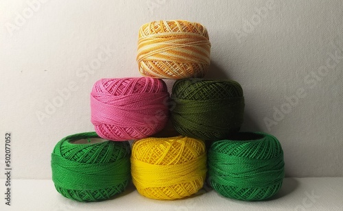 Bunch of double shaded Multicolor mercerized knitting cotton crochet yarn small thread ball or spool stacked together on white table background with copy space. Stitch, needlework, embroidery concept. photo