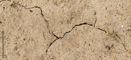 Brown dry and broken clay ground or farm land soil with natural crack because of hot climet, less rainfall drought and global warming. Horizontal background texture pattern close up macro top view.