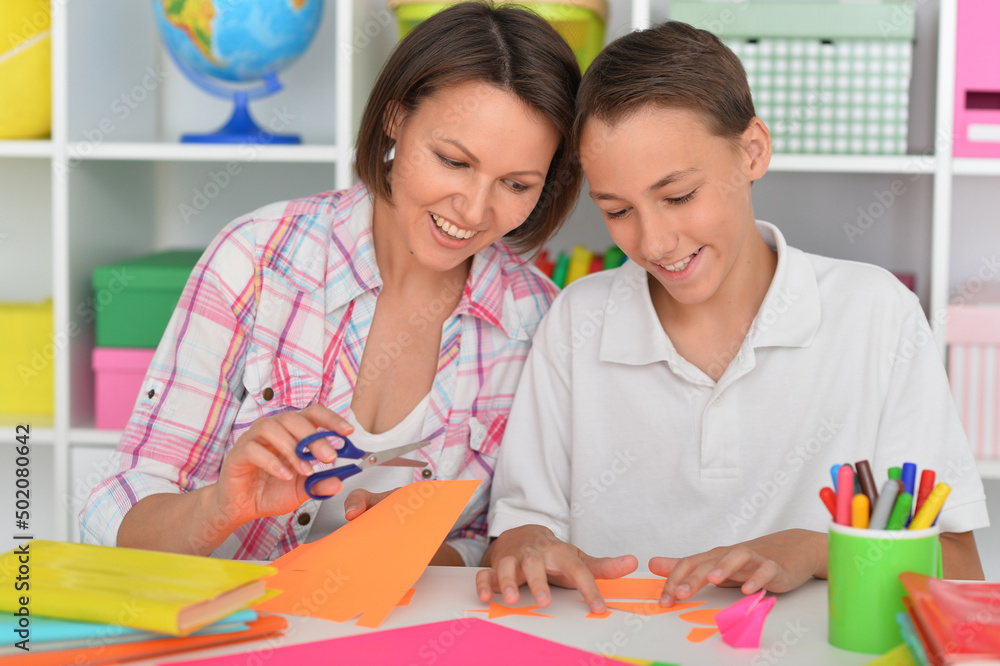 Porait of mother teaches her son to do craft items