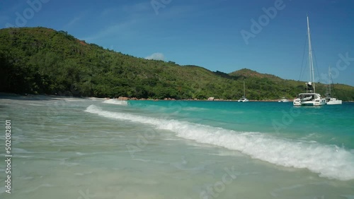 Aerial dolly low above the water over the deserted beach of Anse Lazio