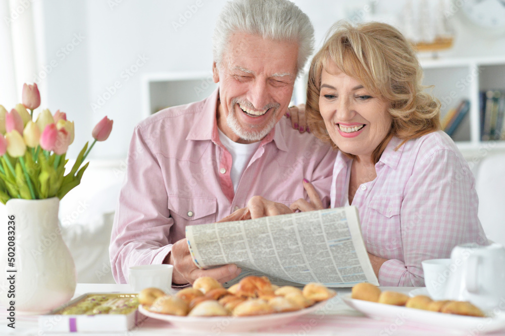 Portrait of senior couple with newspaper at home