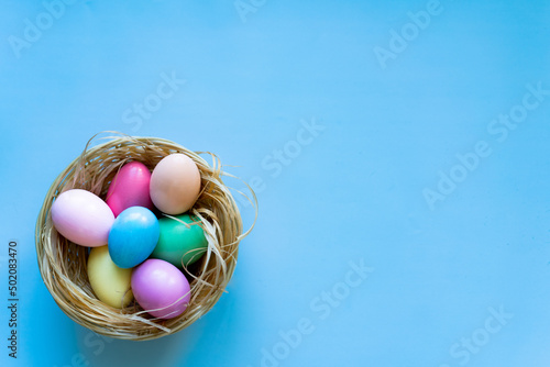 Nest of coloured Easter eggs on blue background