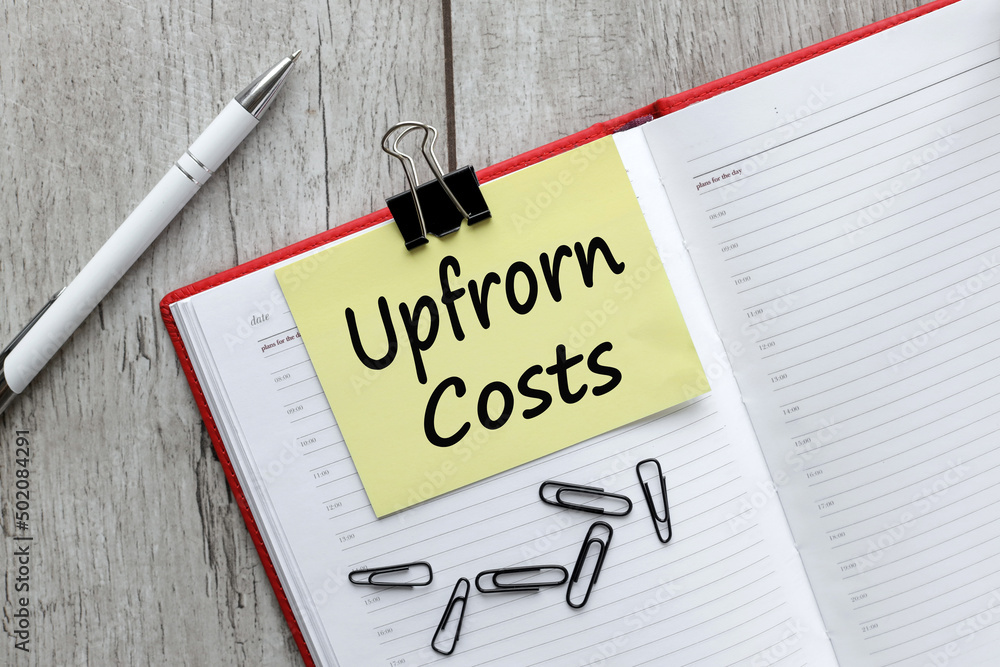 upfrom costs. text on yellow sticker np notepad on wooden background upfrom costs. text on yellow sticker np notepad on wooden background