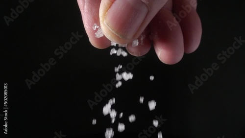 A chef sprinkling coarse sea salt from his fingers.  20x slow motion photo