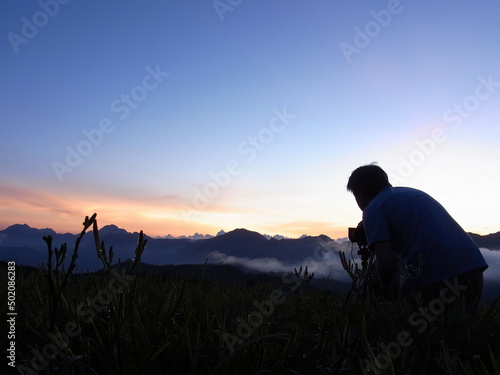 Photographer taking picture of the sunrise view from the Sixty Stone Mountain with daylilies
