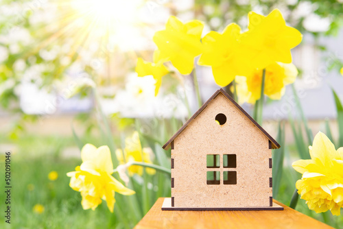 Canvastavla Wooden toy house against vivid daffodils background