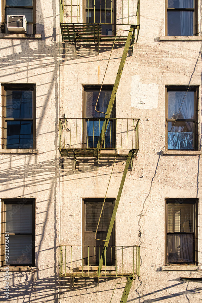 Traditional fire ladders, fire stairs on an old multi story house in New York city creating typical urban feeling 