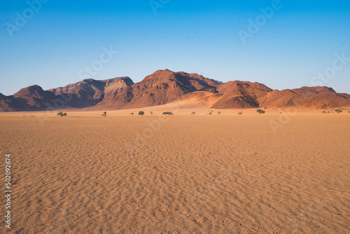 Namibia desert landscape with small mountains in the background behind a wast open sand covered field