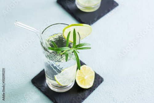 Refreshing drink water with lime and rosemary in glasses with eco straw. Close-up. Copy space photo