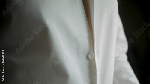 Close up of businessman wears a white shirt. Clip. Close up of man dressing up and adjusting white shirt with cufflinks. The man in the white shirt in the window dress cufflinks.