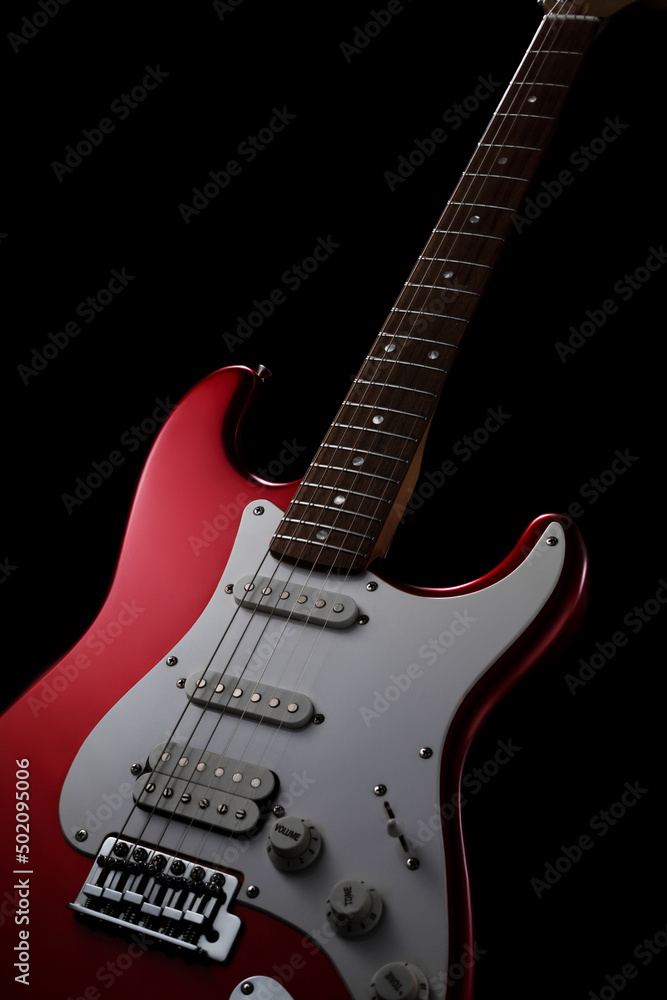 Red electric guitar on a black background. Fender