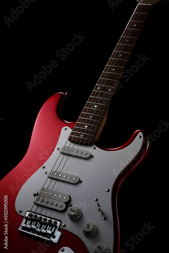 Red electric guitar on a black background. Fender