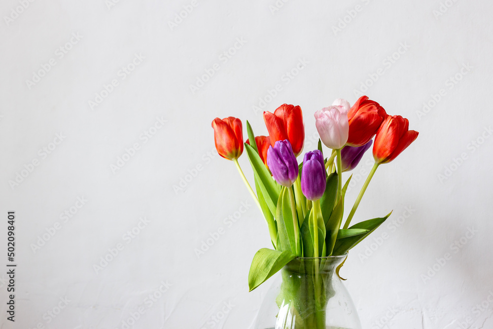 Bouquet of tulips in a glass vase on a white background