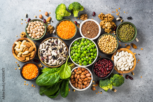 Vegan protein source. Legumes, beans, lentils, nuts, broccoli, spinach and seeds. Top view on stone table. Healthy vegetarian food.
