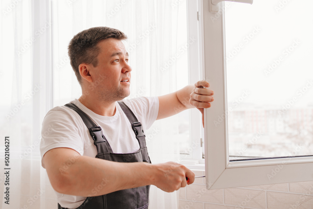 a repairman repairs, adjusts or installs metal-plastic windows in the apartment. a repairman repairs, adjusts or installs metal-plastic windows in the apartment.