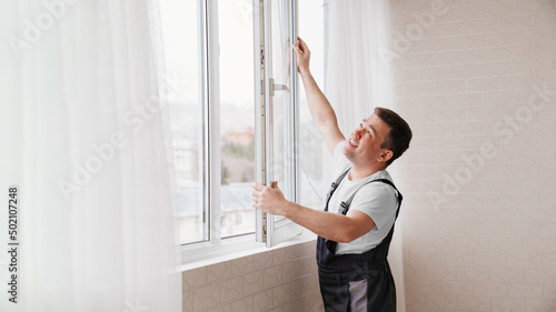 a repairman repairs, adjusts or installs metal-plastic windows in the apartment. © andrey
