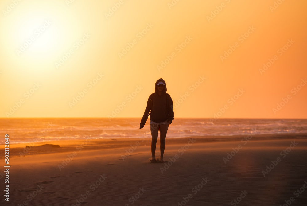 Silhouette of a girl in the desert. Sand dunes and seashore during sunset. Summer landscape in the desert. Hot weather.