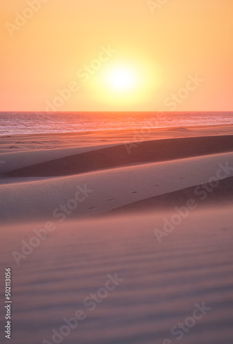 Sand dunes and seashore during sunset. Summer landscape in the desert. Hot weather. Lines in the sand. Landscape without people.