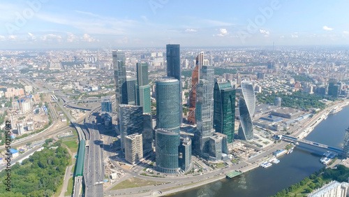 Top view of business center with skyscrapers on background of panorama of city. Action. Cityscape with breathtaking views of mirrored skyscrapers on background blue sky and river